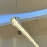 Suspended transparent LED tubular light with prism diffuser and clear PC housing for modern architectural and commercial interior lighting