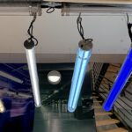 IP67 Ik10 Suspended industrial LED tubular lights in multiple color temperatures and blue illumination, installed in a commercial lighting showroom with clear PC housings