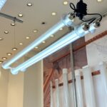 IP67 Ik10 Dual-tube suspended industrial LED tubular light fixture with aluminum connectors, displayed in a showroom alongside clear and frosted tube samples