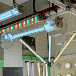 IP67 Ik10 RGB LED tubular lights and adjustable-angle suspended tubes displayed in a lighting showroom with clear PC housings and multi-color effects