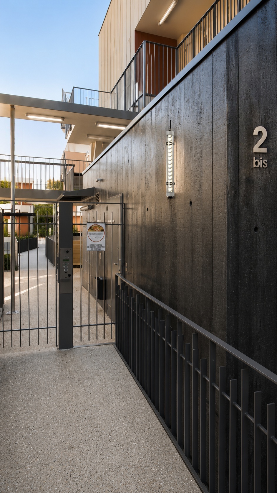 Residential entrance lighting solution with tubular LED fixtures for apartment access routes, façade walls, and shared outdoor areas